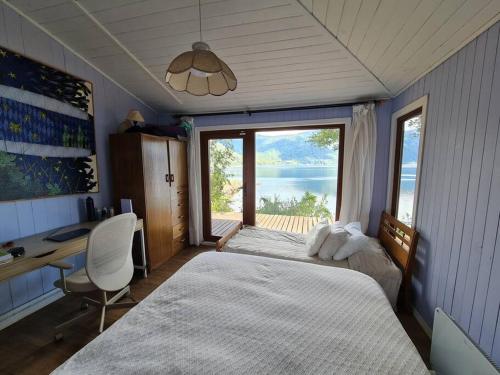 1 Schlafzimmer mit 2 Betten, einem Schreibtisch und einem Fenster in der Unterkunft Casa a orilla del lago in Pucón