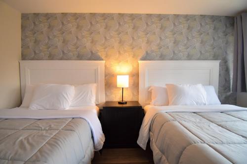 a hotel room with two beds and a lamp at Green Harbor Hotel in Marshfield