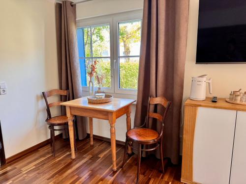- une table et des chaises dans une chambre avec fenêtre dans l'établissement Garten Apartment am Fluss, à Eriskirch