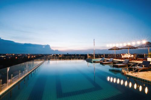 a large swimming pool with chairs and umbrellas at Qualia De Hôtel Hoi An - Rooftop Bar City View in Hoi An