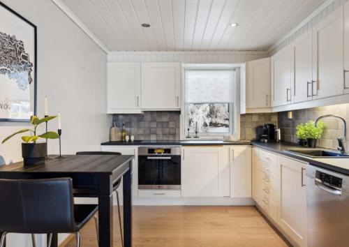 a kitchen with white cabinets and a black table at Heimdal nær Granåsen in Trondheim