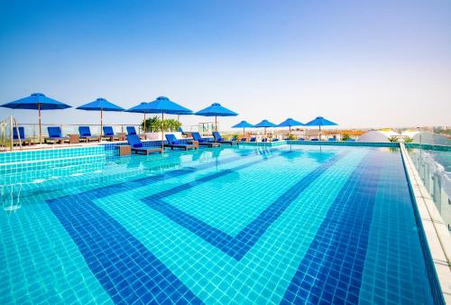 a large swimming pool with blue chairs and umbrellas at Qualia De Hôtel Hoi An - Rooftop Bar City View in Hoi An