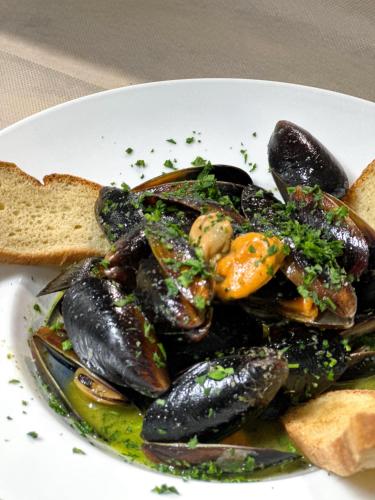 a plate of mussels and bread on a table at Hotel La Bussola in Finale Ligure