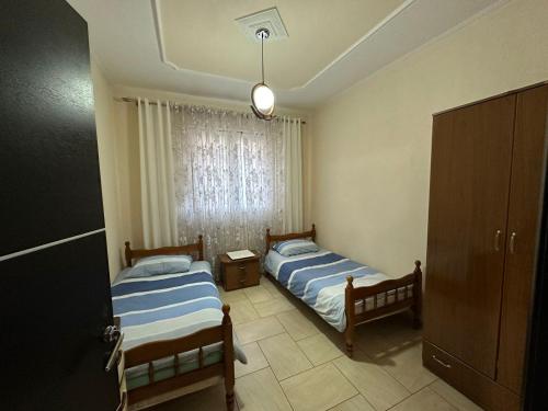2 Betten in einem kleinen Zimmer mit Fenster in der Unterkunft Vila Mani in Durrës