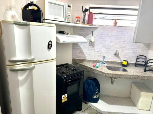 una pequeña cocina con nevera y fregadero en Confortável quarto e sala com Manobrista, Wi-fi, Tv Smart - Apto 208, en Maceió