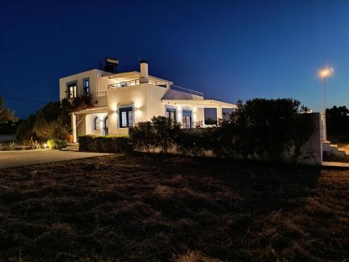 una casa bianca seduta in cima a una collina di notte di Nautilus Beach House a Paradisi