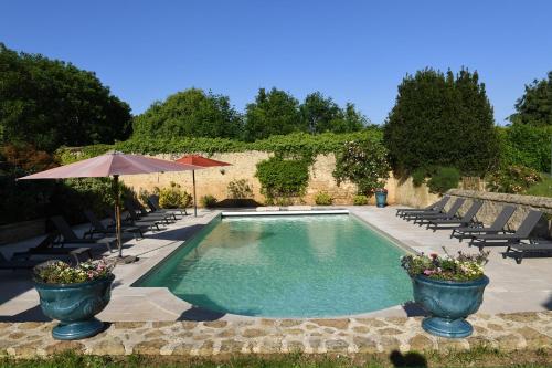 una piscina con sillas y sombrilla en 24H LE MANS Château de Lauresse chambres d'hôtes Luxe en Le Mans