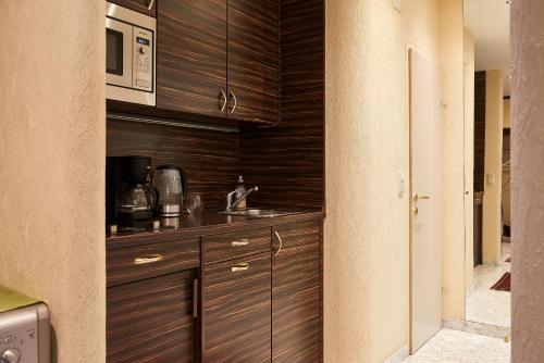 a kitchen with wooden cabinets and a microwave at Exclusive Central Spacious Apartment in Innere Stadt w Free Parking in Vienna