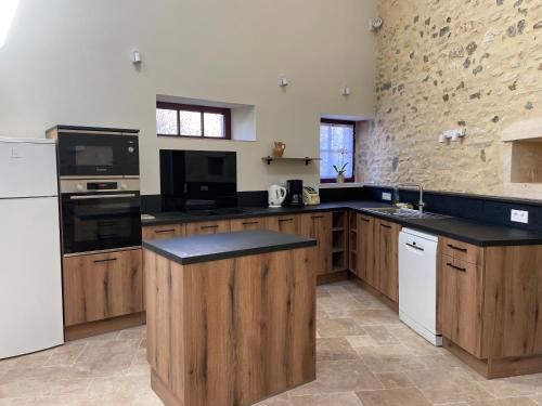 une cuisine avec des comptoirs noirs et des armoires en bois dans l'établissement La Maison des Poètes 6 personnes à Treigny Perreuse, à Perreuse