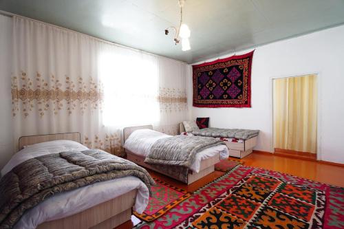 a bedroom with two beds and a rug at Guest House Bereke in Kyzart village in Bagysh