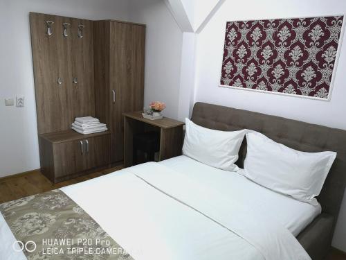 a bedroom with a white bed and a wooden cabinet at Casa Hortensia in Tăşnad