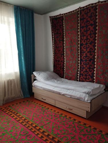 a bedroom with a bed with a headboard and a rug at Guest House Bereke in Kyzart village in Bagysh