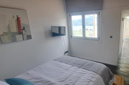 ein weißes Schlafzimmer mit einem Bett und einem Fenster in der Unterkunft La Casita de Mari in Moaña