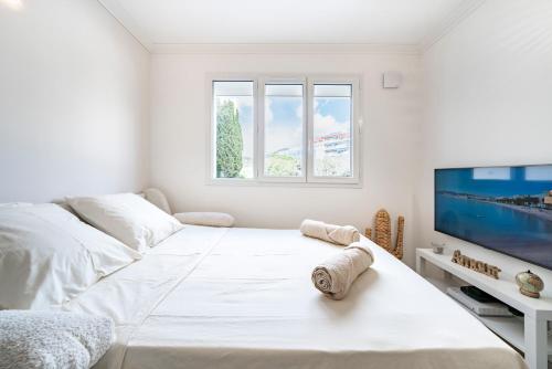 une chambre blanche avec un lit et une télévision à écran plat dans l'établissement Studio Banane 2 min croisette mitoyen Martinez, à Cannes