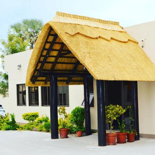 a large straw umbrella in front of a building at Etang Guesthouse in Nata
