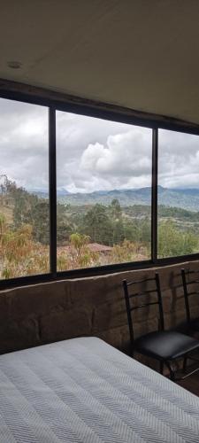 a bedroom with a large window with a bed and two chairs at Hospedaje Leonor in Cuenca