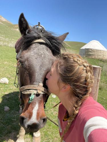 a woman kissing a horse in a field at Guest House Bereke in Kyzart village in Bagysh