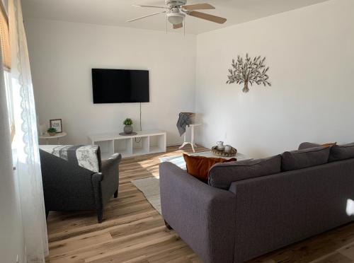 a living room with two couches and a flat screen tv at Lovely 2- Bedroom Duplex in Pueblo West in Pueblo West