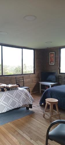 a bedroom with a bed and a table and some windows at Hospedaje Leonor in Cuenca
