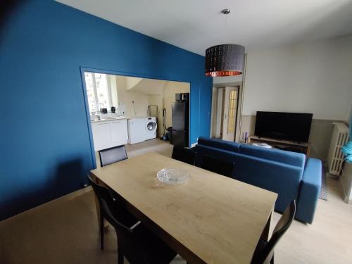 uma sala de estar com uma mesa e uma parede azul em Appartement BLUEMA 2 chambres RdC em Vitré