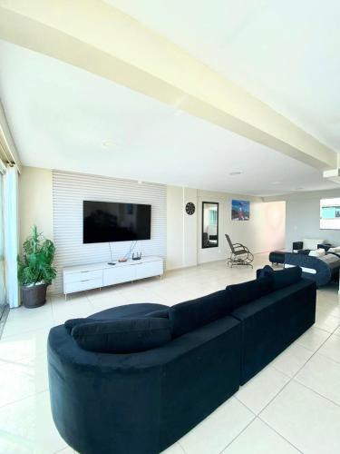 a living room with a large black couch and a flat screen tv at Cobertura com Piscina Praia Grande Vista Mar in Arraial do Cabo