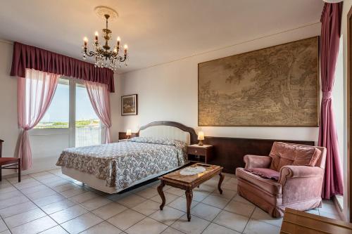 a bedroom with a bed and a chair and a chandelier at Hotel Eden in Grado
