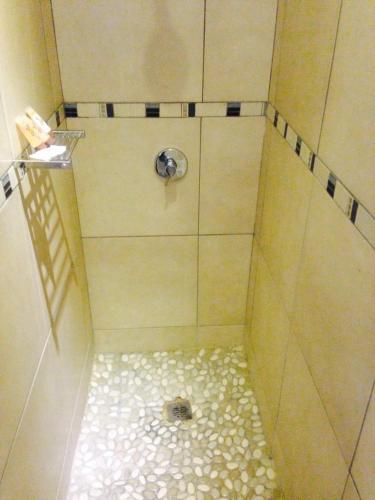 a shower with a tile floor and a drain at Sandriver Resort in Musina
