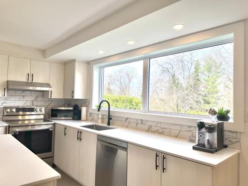 a kitchen with white cabinets and a large window at Condo sur 2 étages in Saint-Faustin