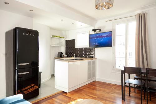 une cuisine avec des armoires blanches et un réfrigérateur noir dans l'établissement Charmant appartement - 4 couchages à proximité d'Opéra, à Paris