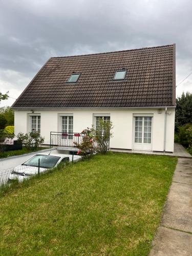 a white house with a black roof and a yard at Helene in Torcy