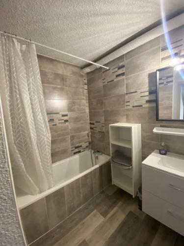 y baño con bañera y lavamanos. en Appartement 50m2 vue imprenable avec garage draps et serviettes compris, en Villard-de-Lans