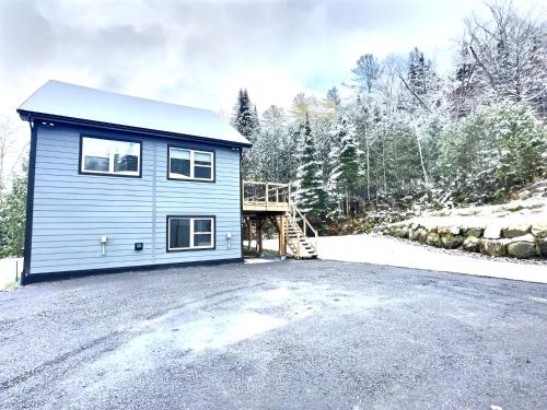 a blue tiny house on a gravel lot at Le domaine du Sous-Bois in Mont-Blanc