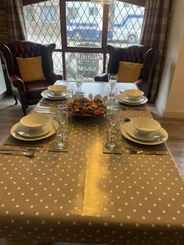 a dining room table with plates and glasses on it at The Coach House at BYRE HOUSE in Coalpit Heath