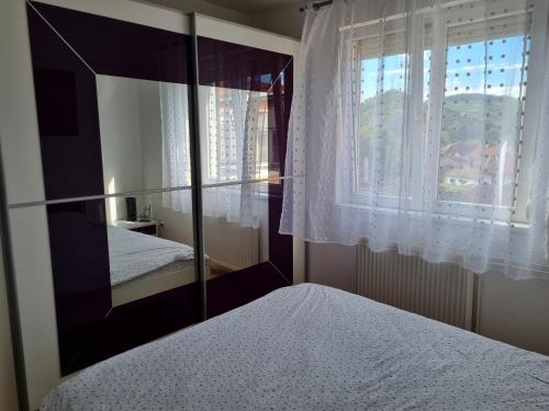 ein Schlafzimmer mit einem Spiegel, einem Bett und einem Fenster in der Unterkunft Stan u centar in Pirot