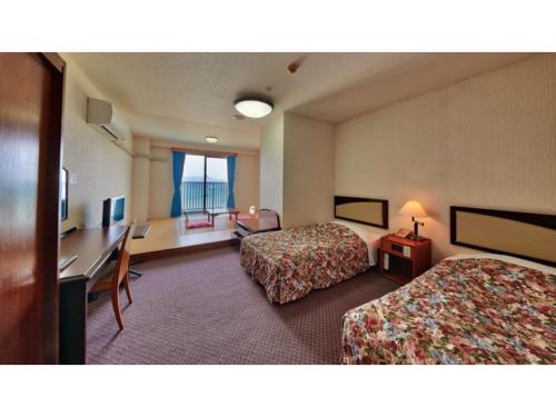 une chambre d'hôtel avec deux lits et un bureau dans l'établissement Miyuki Hamabaru Resort - Vacation STAY 13397v, à Atsutabaru