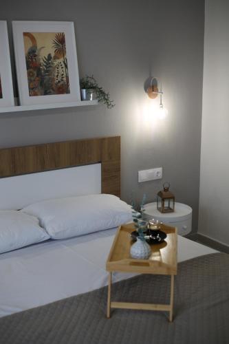 a bedroom with a white bed and a wooden table at Our Home-Fully renovated apartments and studios by the sea in Nikiti