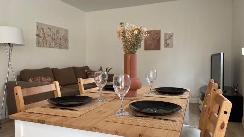 une table en bois avec des assiettes et des verres à vin dessus dans l'établissement Appartement 2 pièces entre paris et Disney, à Pontault-Combault