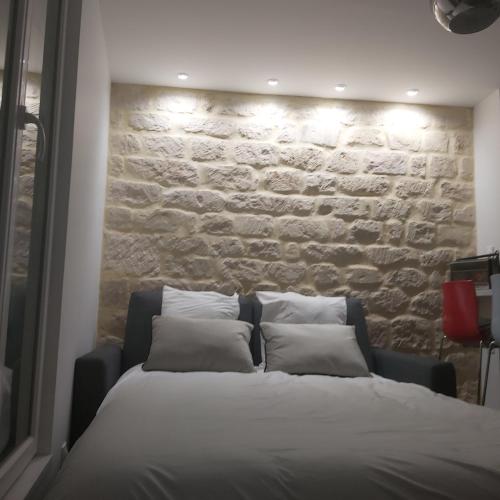 un lit dans une chambre avec un mur en pierre dans l'établissement La Bastille, à Paris
