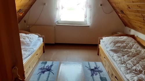 two beds in a small room with a window at Ferienwohnung Hähnlein in Steinach