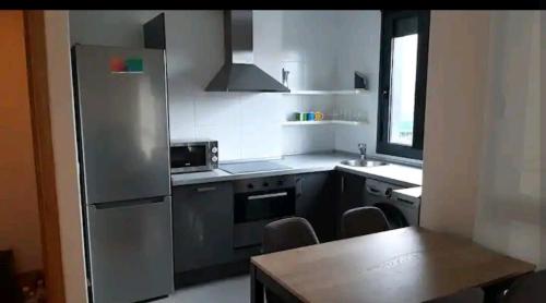 eine Küche mit einem Kühlschrank aus Edelstahl und einem Tisch in der Unterkunft El Sermar in Santoña