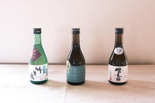 sikari Vacation STAY 95401v في Takashima: ثلاث زجاجات من النبيذ على طاولة