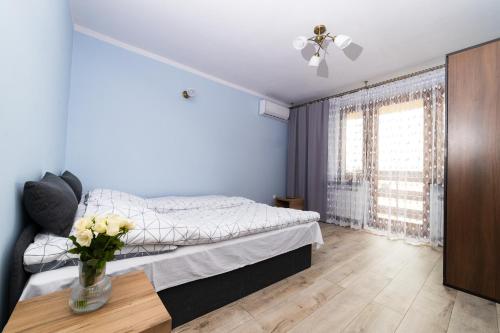 1 dormitorio con 1 cama y un jarrón de flores sobre una mesa en Apartament Na Bajkowej en Busko-Zdrój