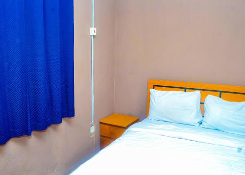 1 dormitorio con 1 cama con cortina azul en Miccom Golf Hotel and Resort, en Ikirun
