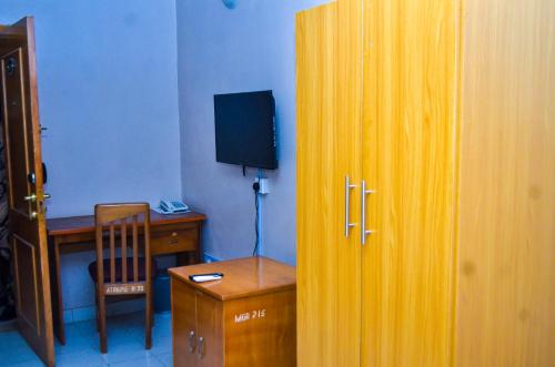 Habitación con escritorio y puerta de madera con mesa y silla. en Miccom Golf Hotel and Resort, en Ikirun