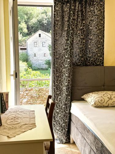 a bedroom with a bed and a table and a window at Venera Apartman in Škaljari