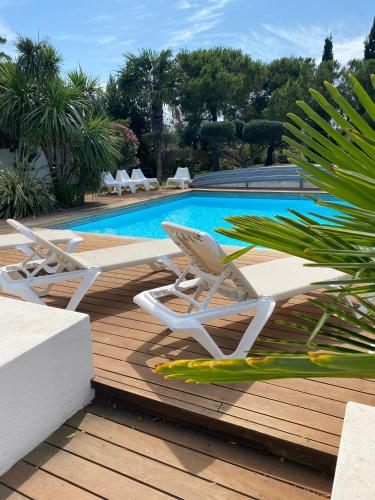 2 chaises longues blanches et une piscine dans l'établissement La villa de Michèle, à Marseillan