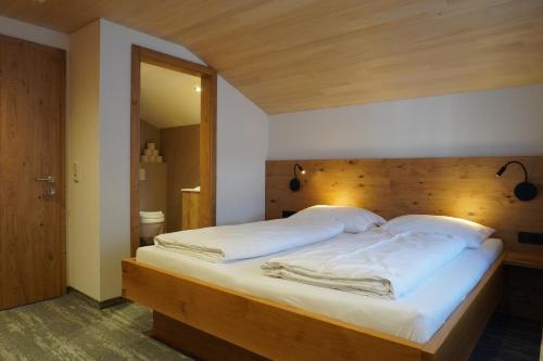 a bedroom with a large bed with a wooden headboard at Pension Edelweiss in Damuls