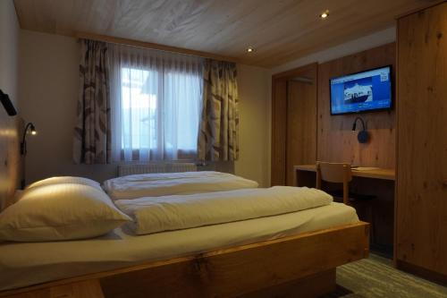 a bedroom with a bed with a window and a television at Pension Edelweiss in Damuls