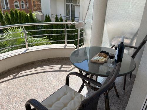 a glass table and chairs on a balcony with a bottle of wine at Villa Dislievski in Ohrid