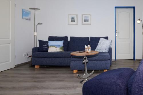 uma sala de estar com dois sofás azuis e uma mesa em FeWo am Dorfteich em Lemkenhafen auf Fehmarn